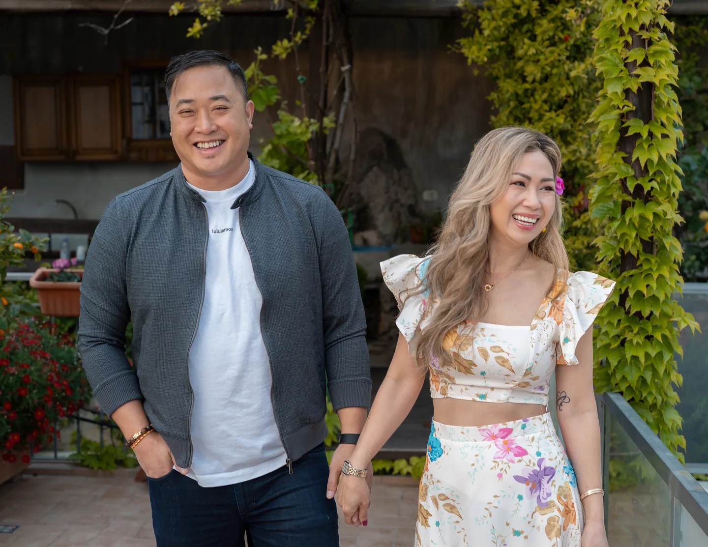 The couple holding hands beside the garden plants