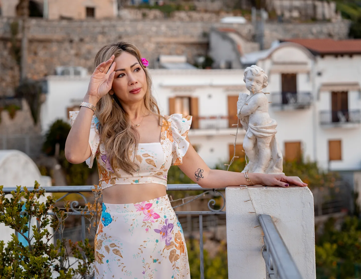 Anh brushing her hair back beside the terrace pillar