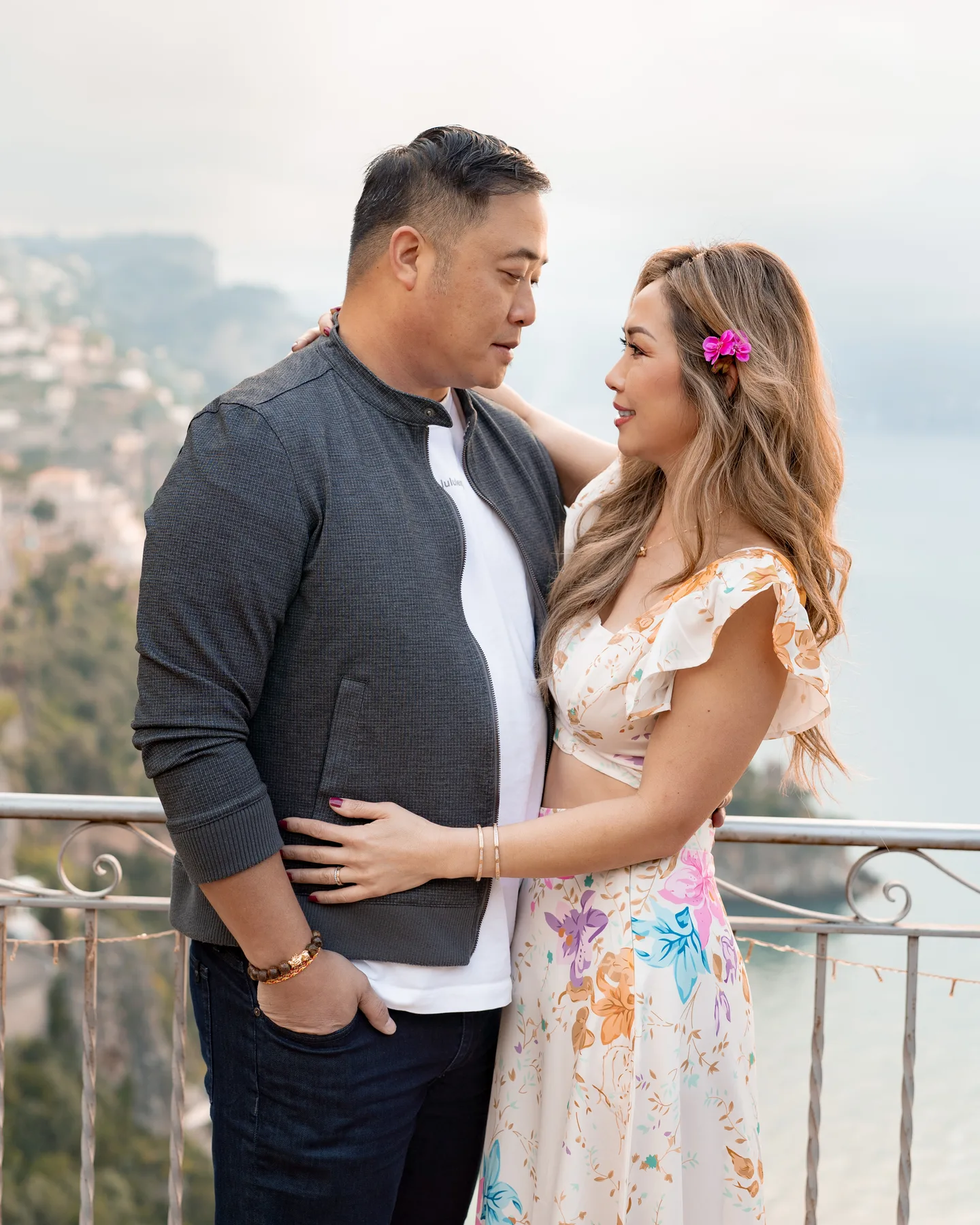 The couple facing one another at the balcony railing