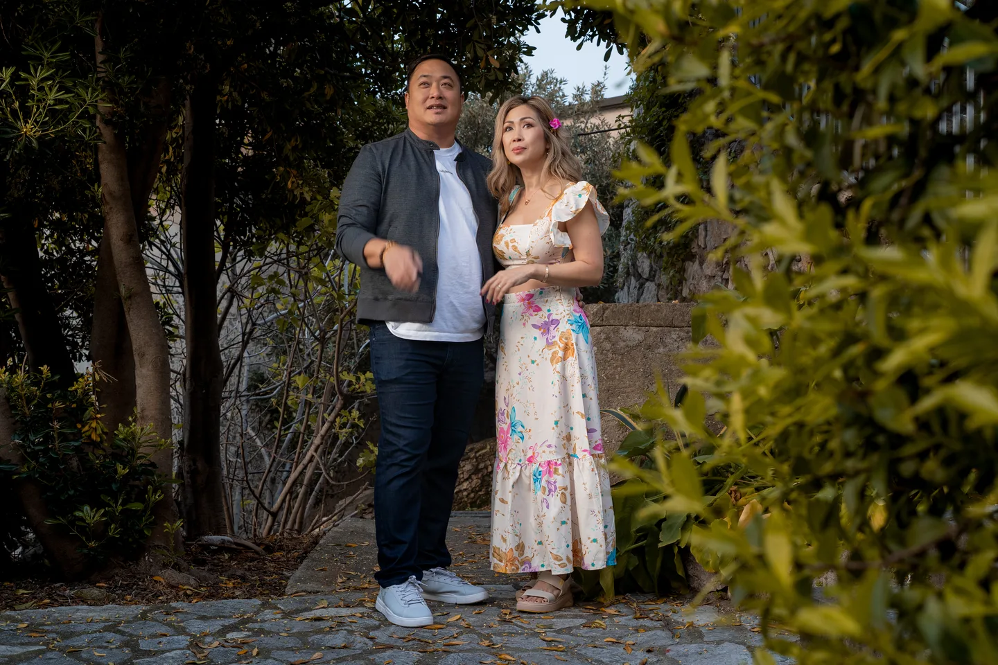 The couple laughing beneath an arch of foliage