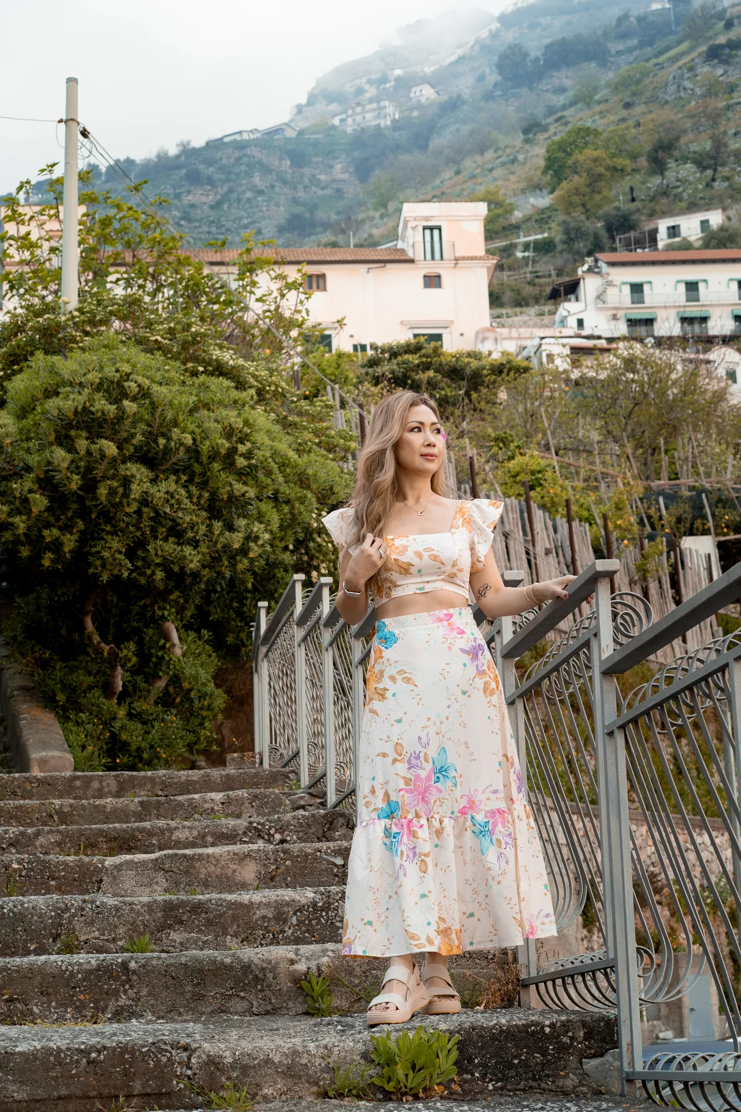 Anh standing on a stone staircase above the village
