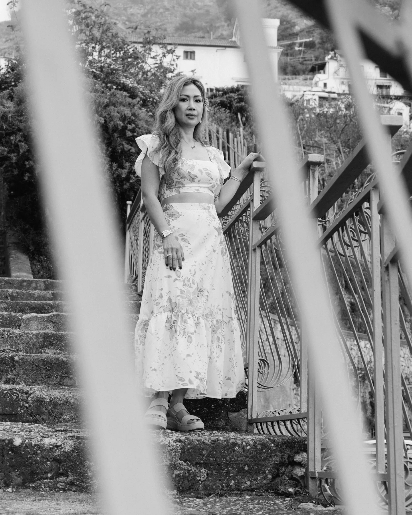 Anh on the stone steps, photographed through the railing in black and white