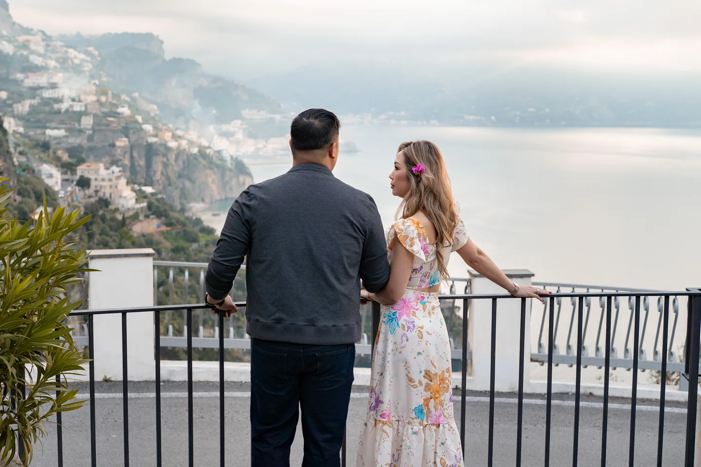 The couple looking out over the coast from the railing