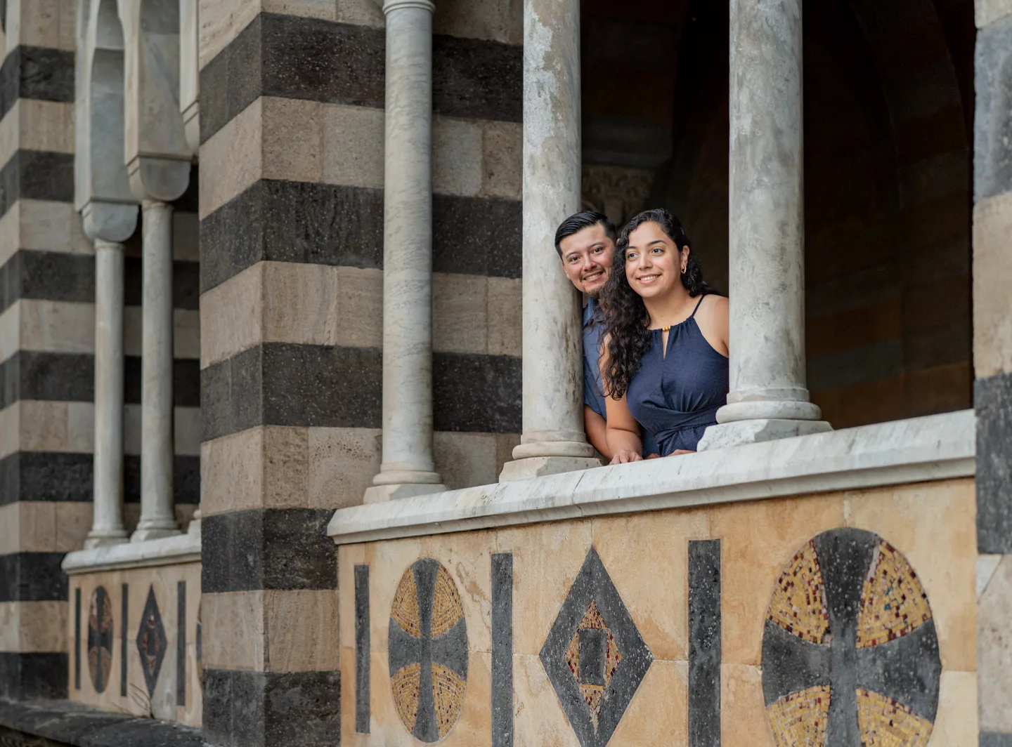 The couple leaning out between the cathedral columns