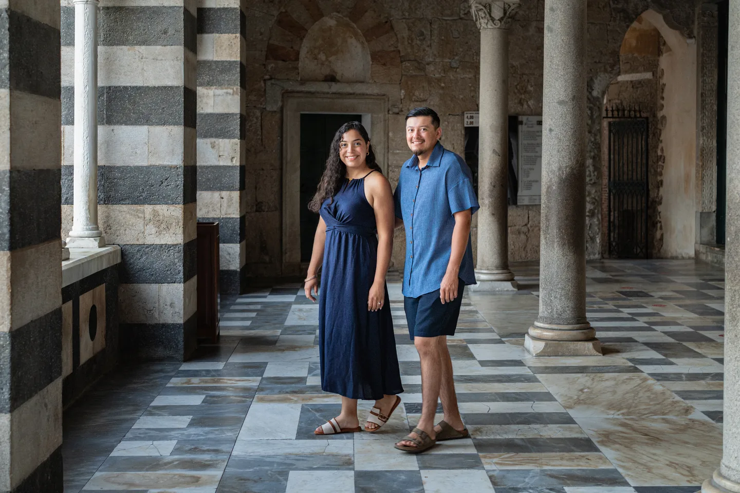 The couple standing together in the cathedral arcade