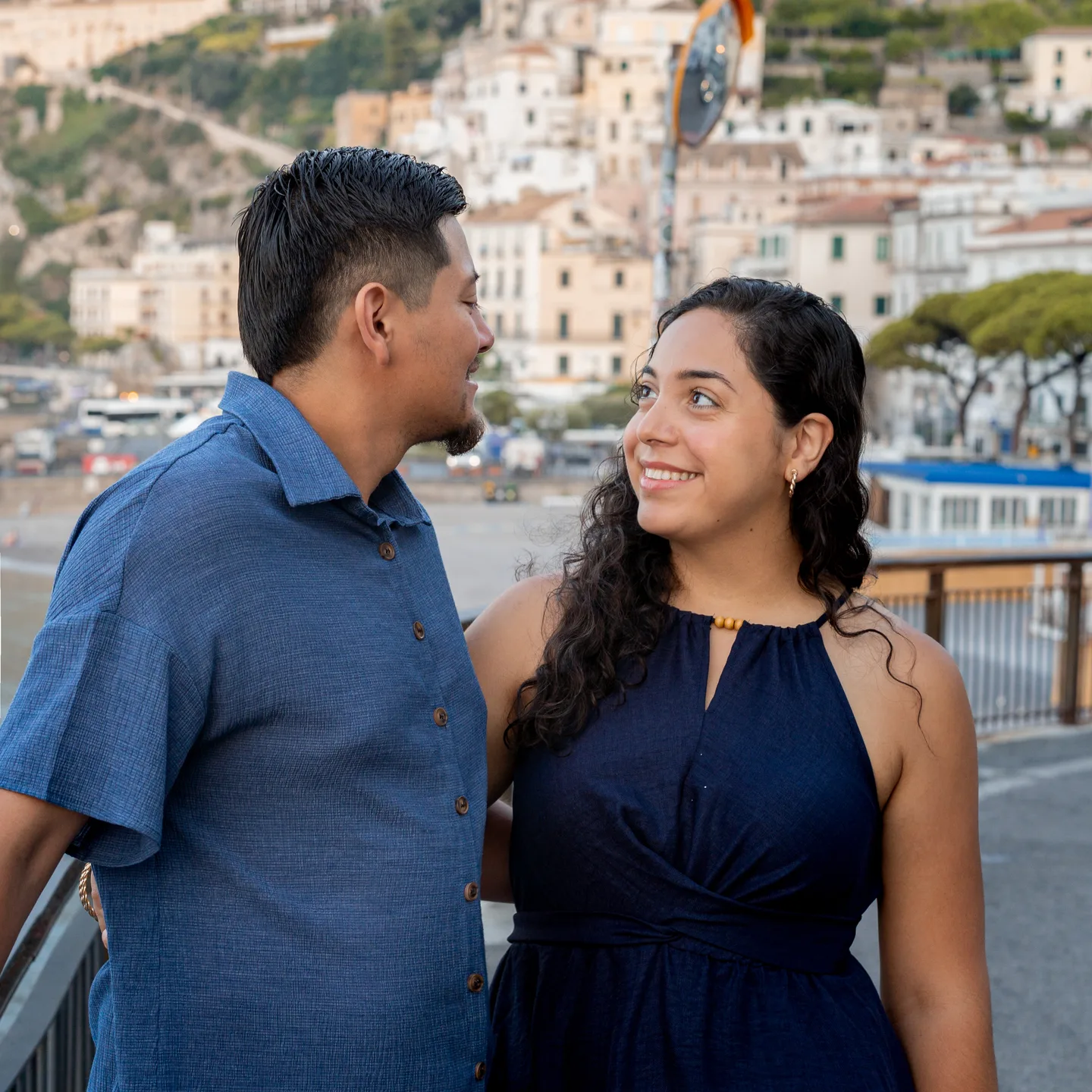 The couple looking at one another with Amalfi behind them