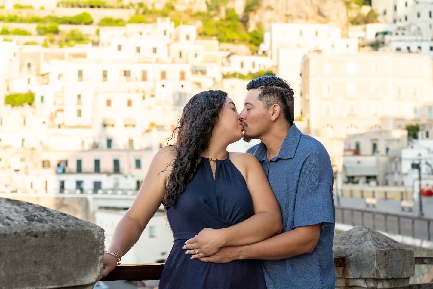 The couple kissing beside the stone railing