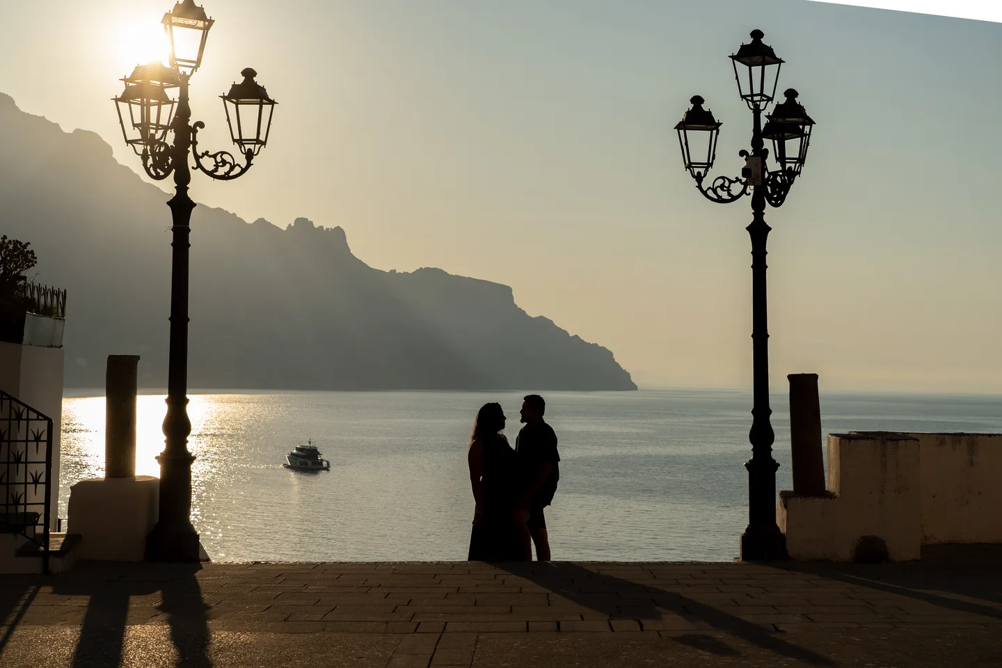 The couple silhouetted between two street lamps above the sea