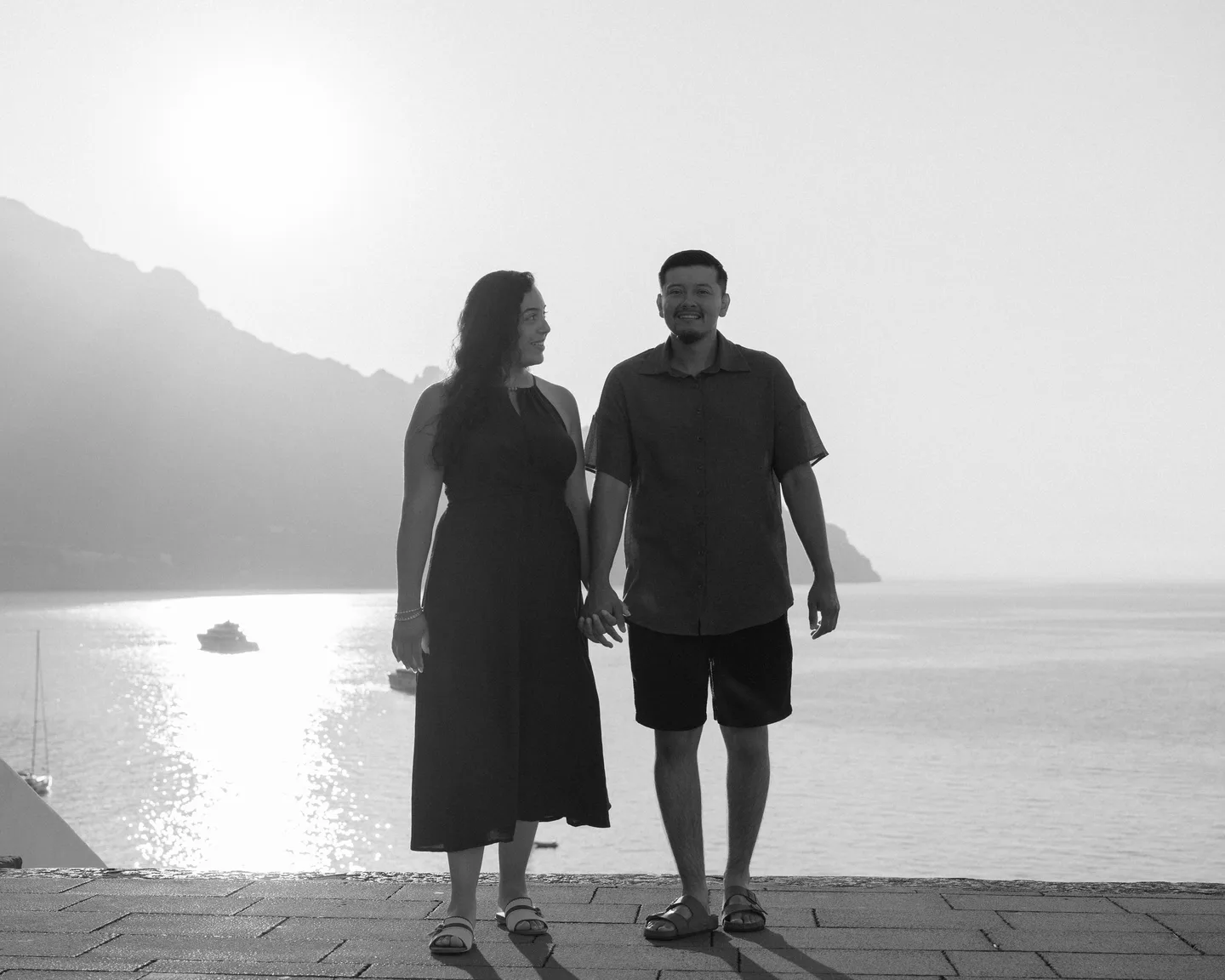 A black-and-white photograph of the couple walking above the sea
