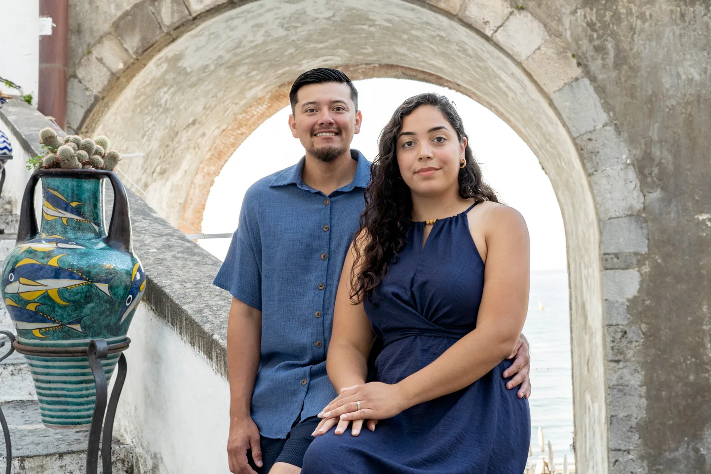 The couple beside a ceramic vase beneath a stone arch