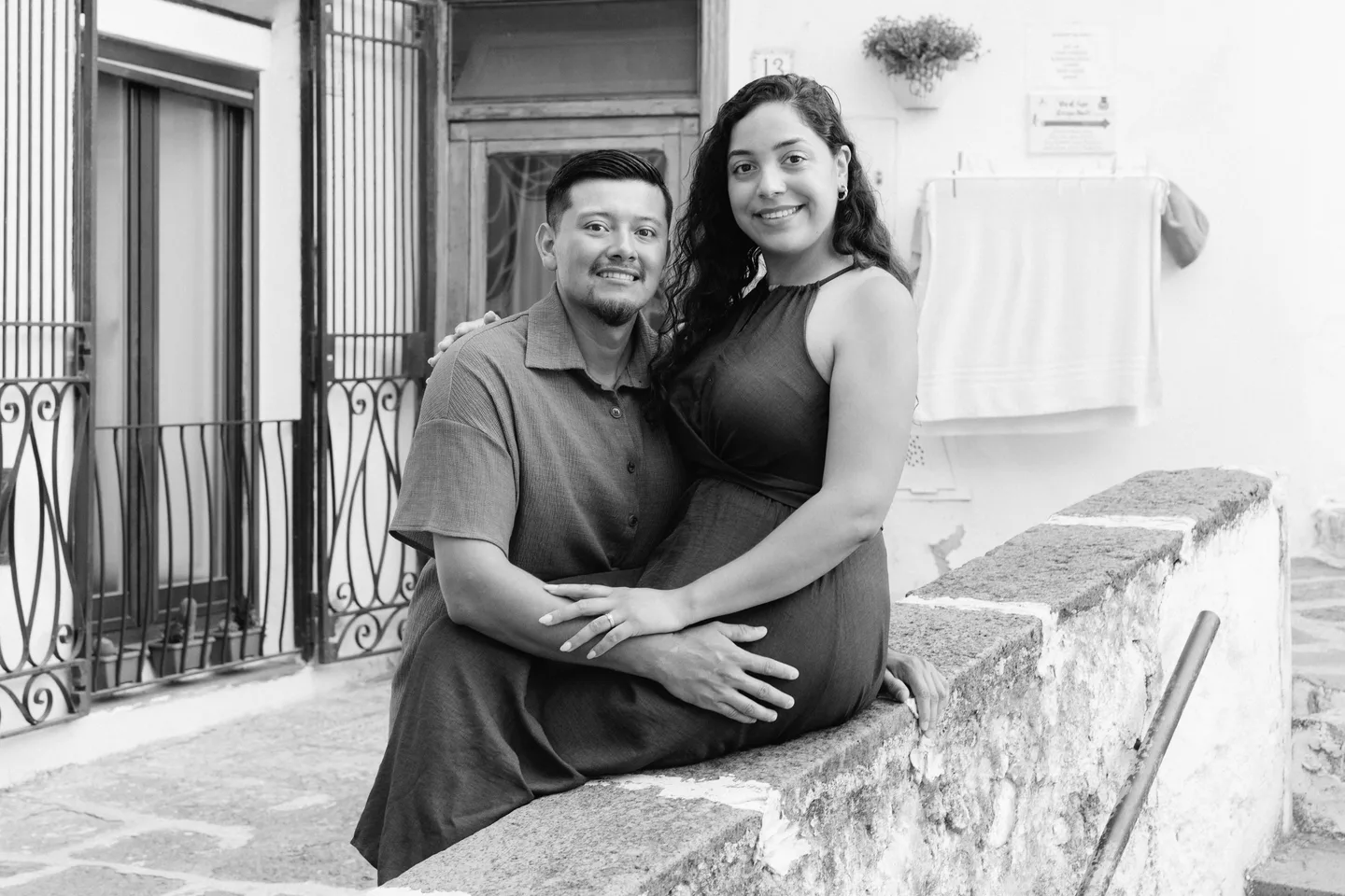 A black-and-white portrait of the couple beside the stone railing