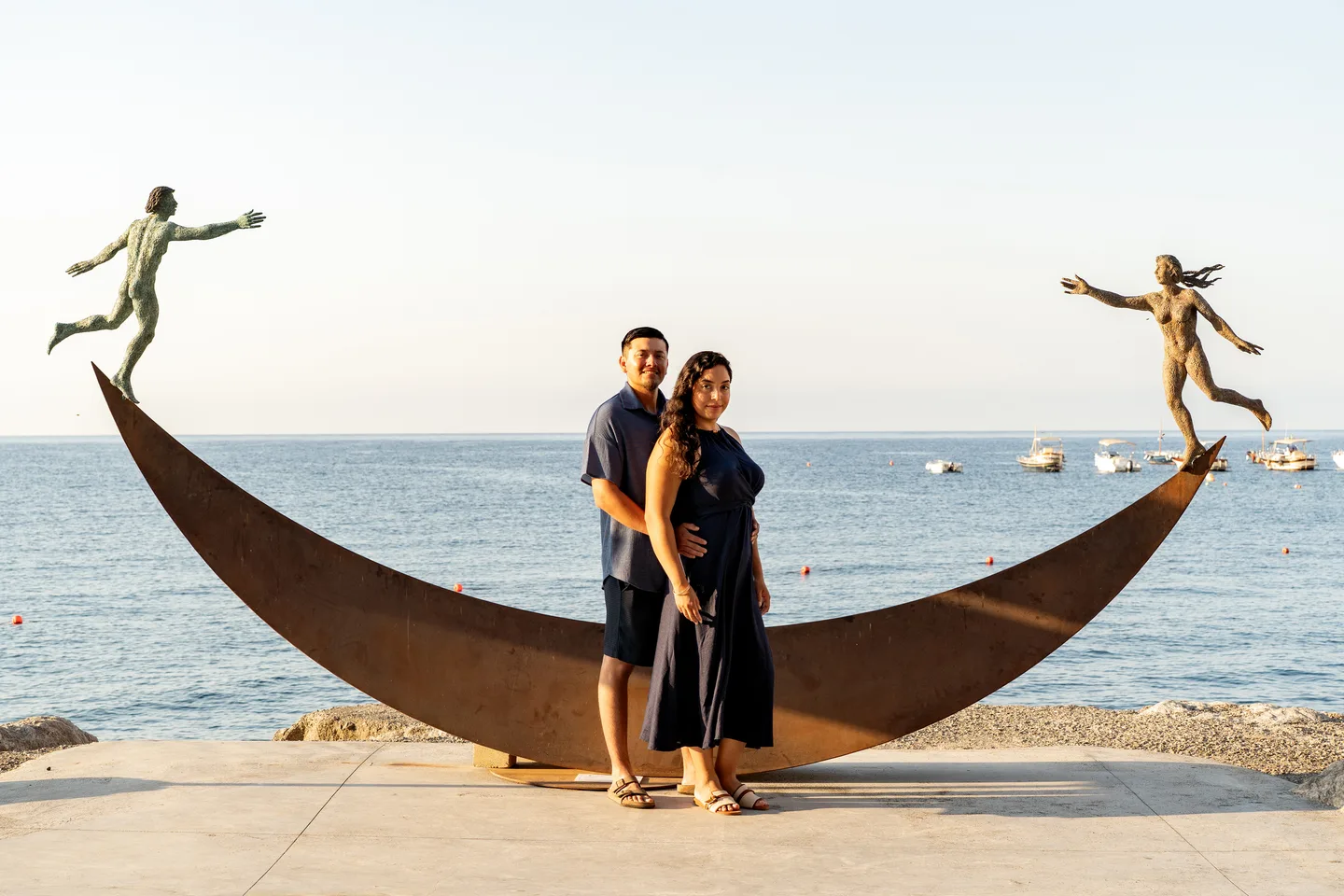 The couple in front of a curved seaside sculpture