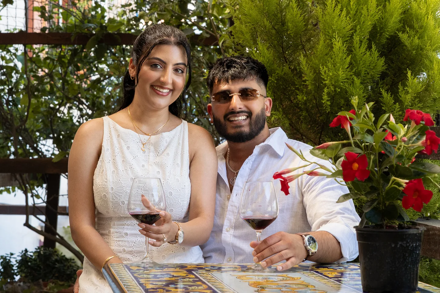 The couple smiling with wine glasses in the garden