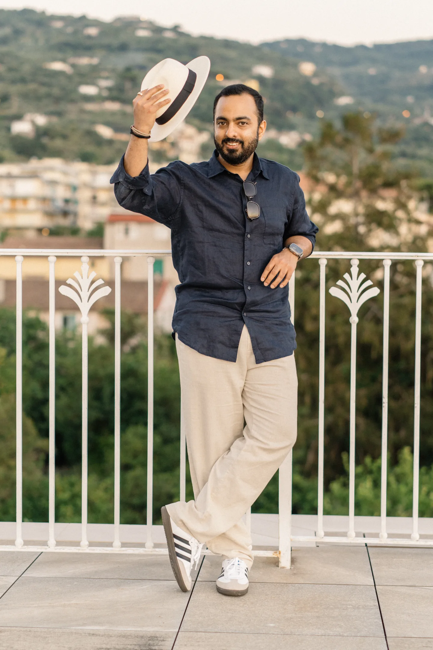 Jatin lifting his hat beside the terrace railing