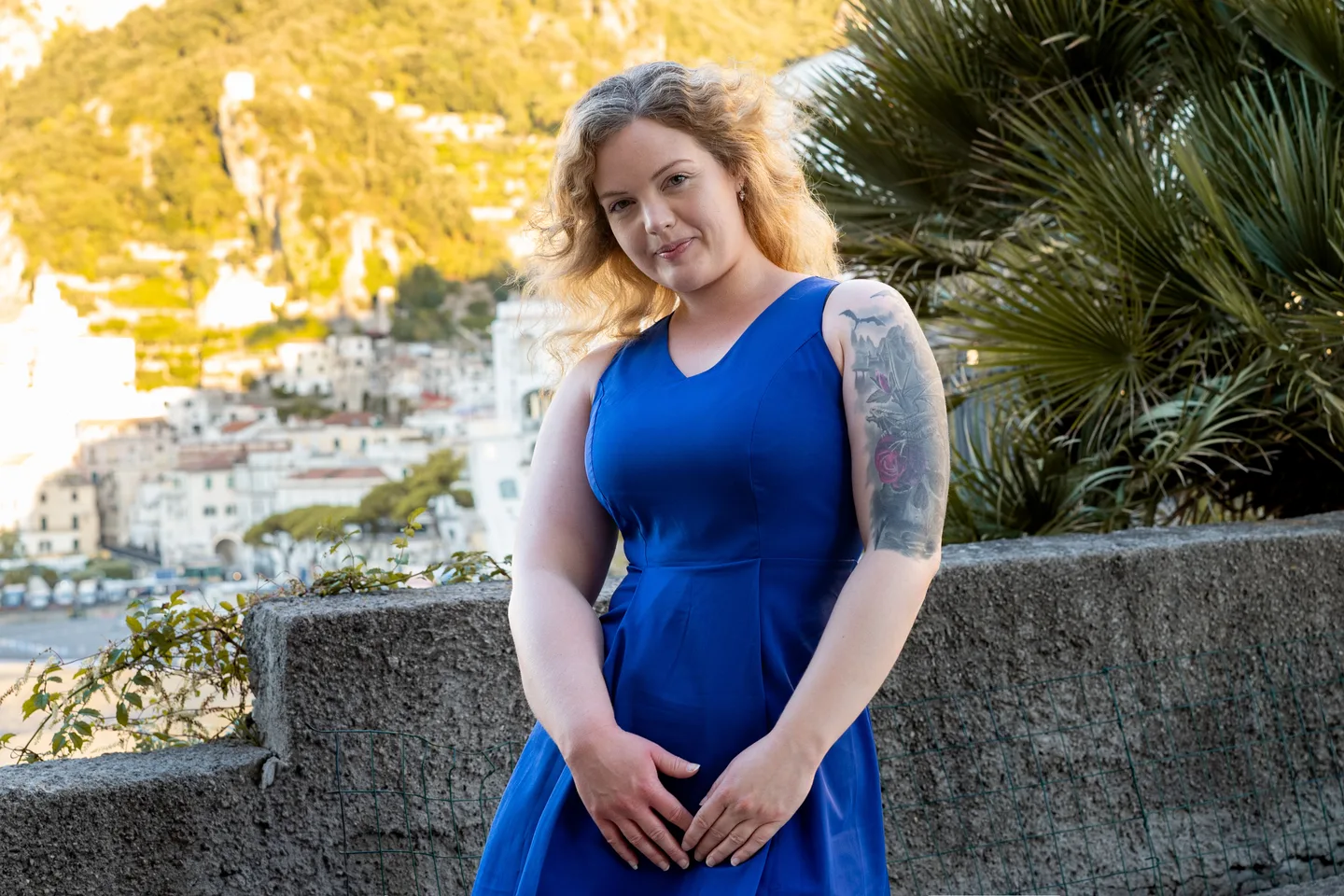 Nathalie in a blue dress beside the palm trees