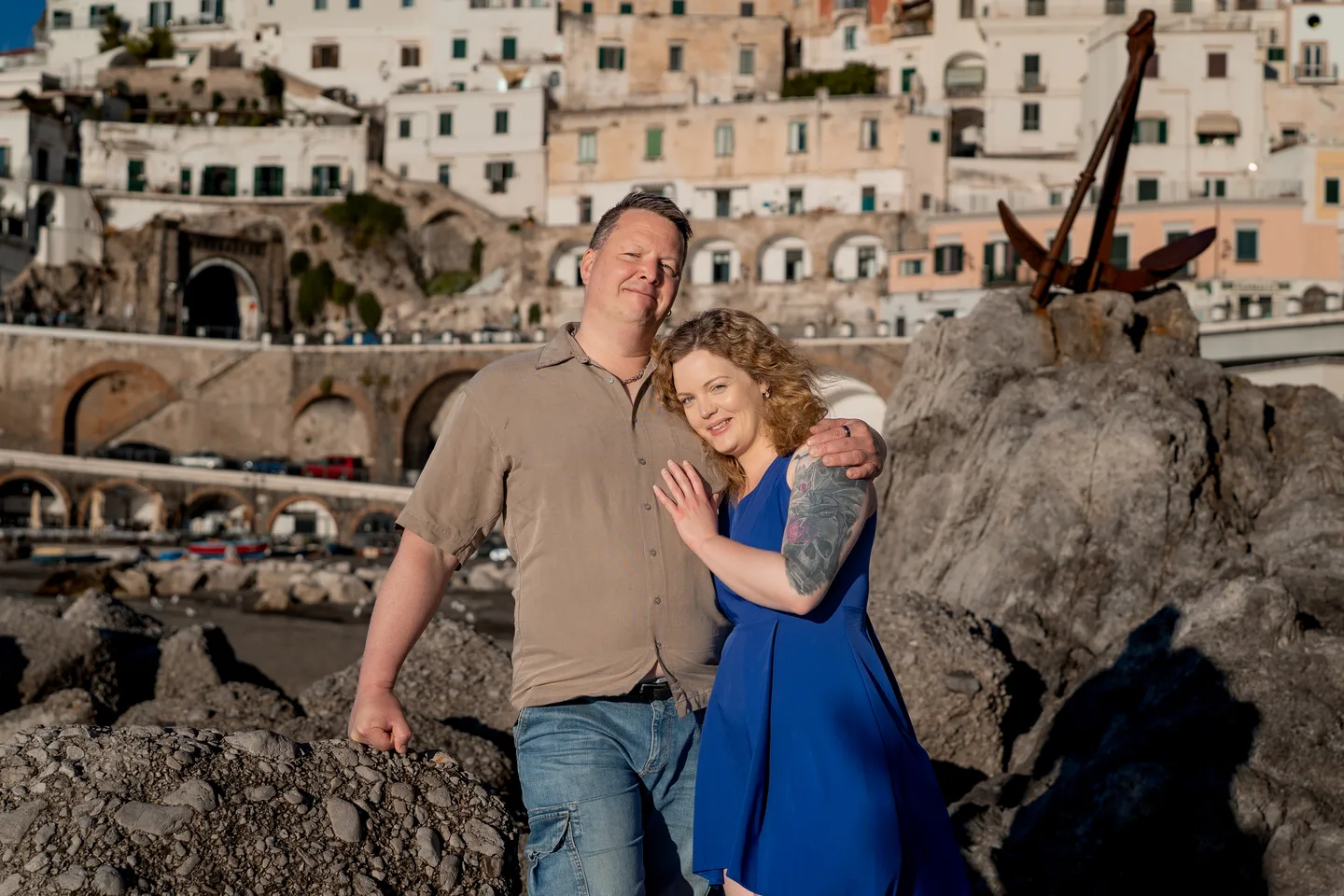 The couple sitting together on the waterfront rocks