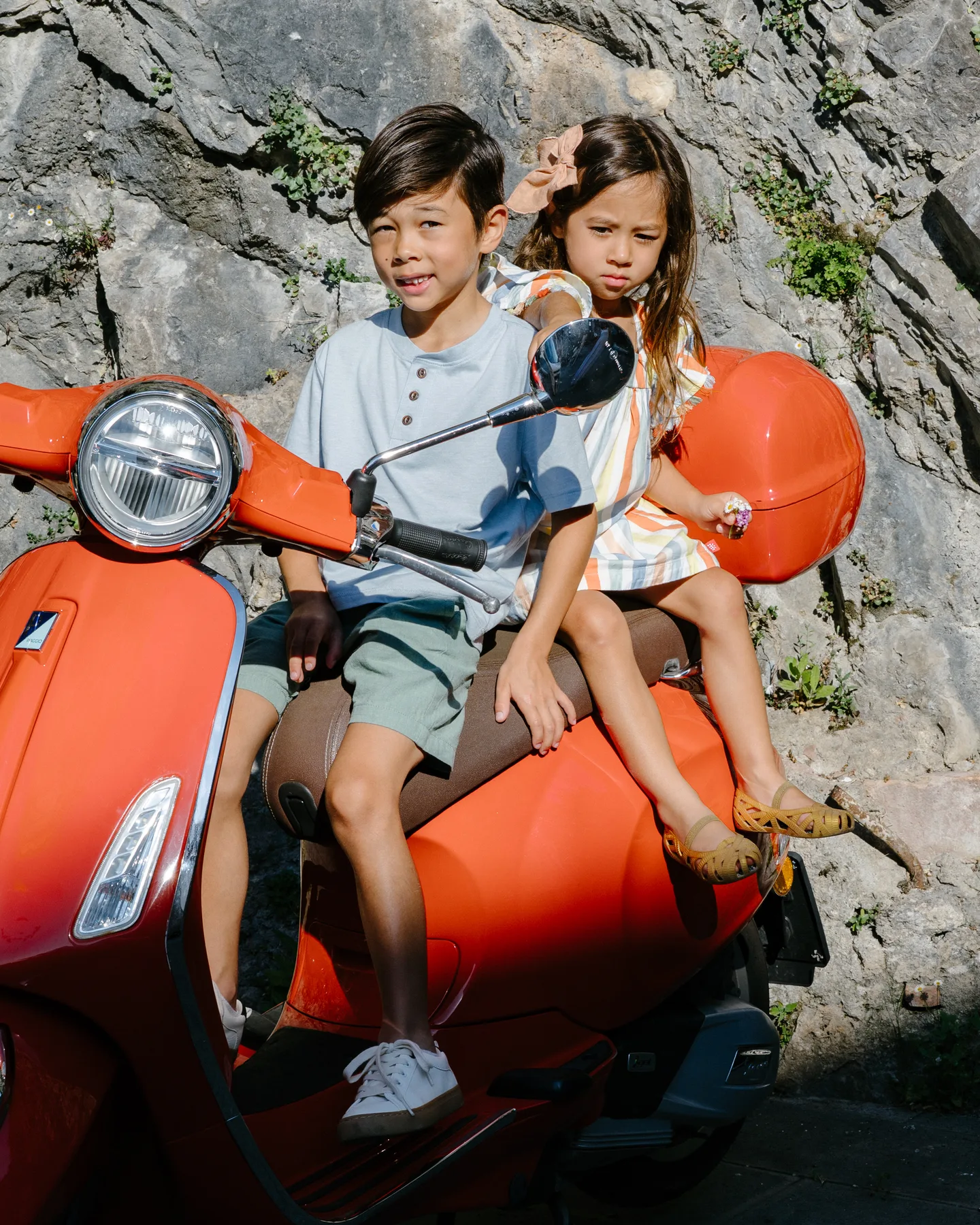 The children sitting together on a red scooter