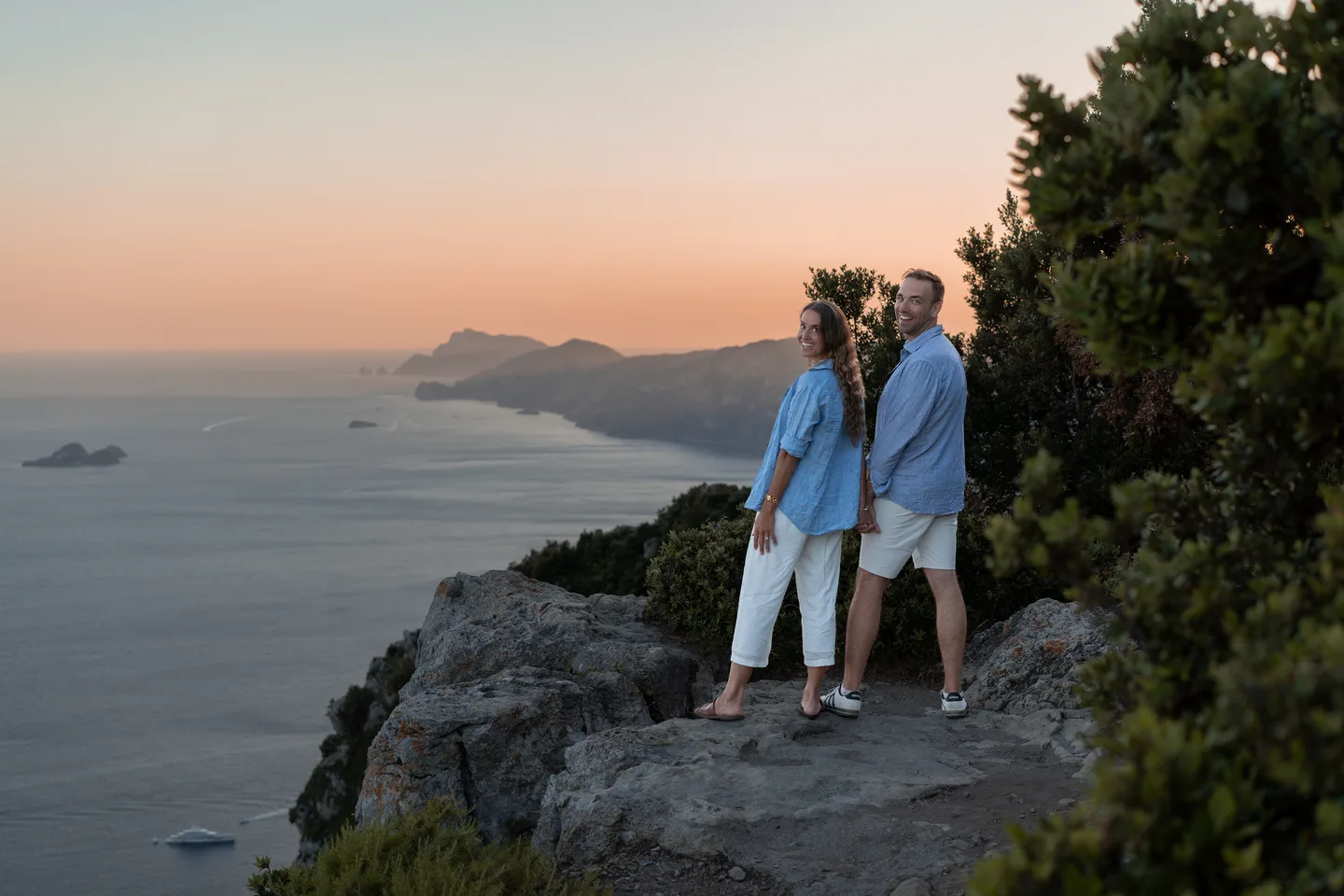 The couple standing against the evening coastline