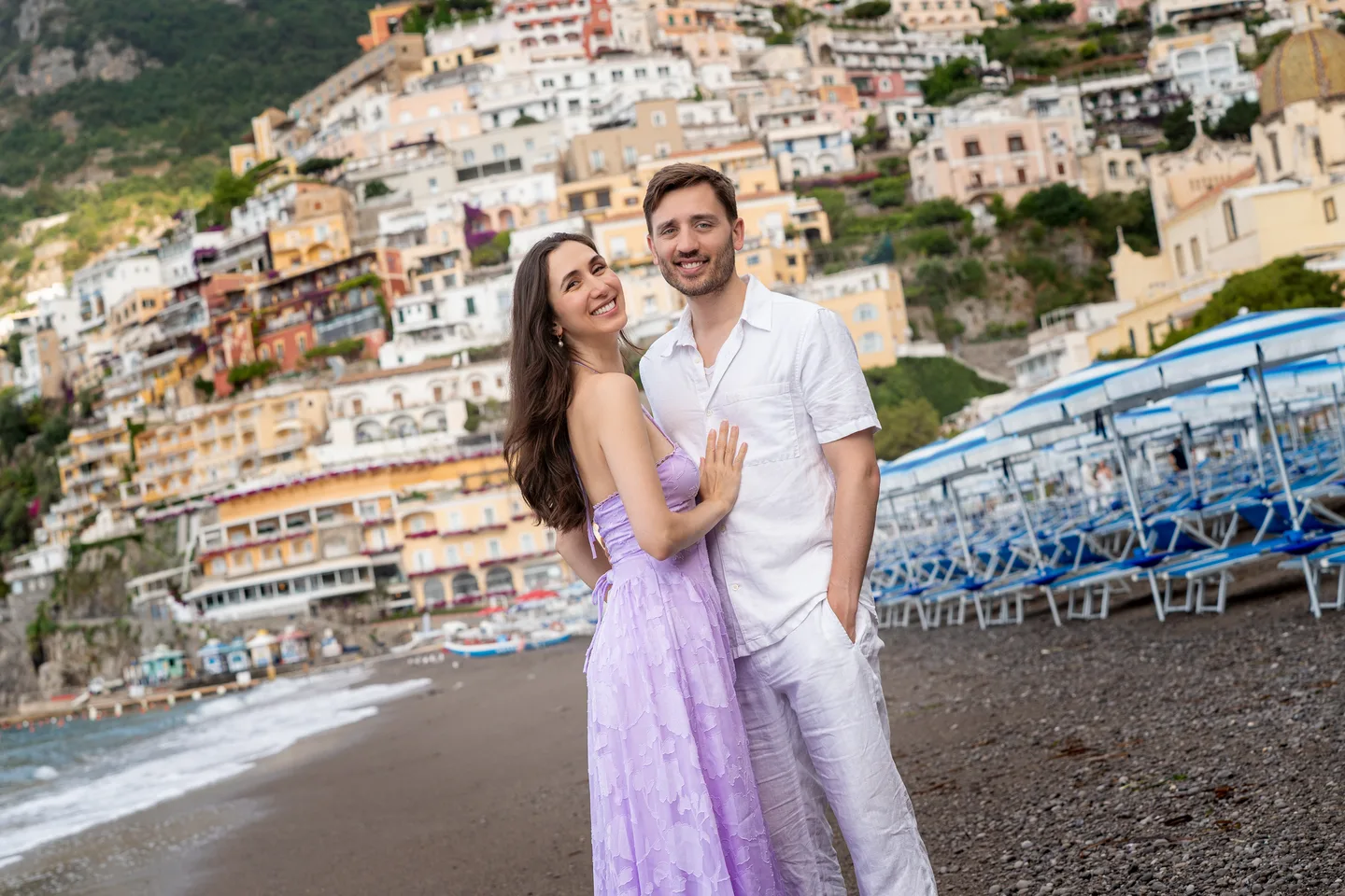 The couple smiling with the town behind them