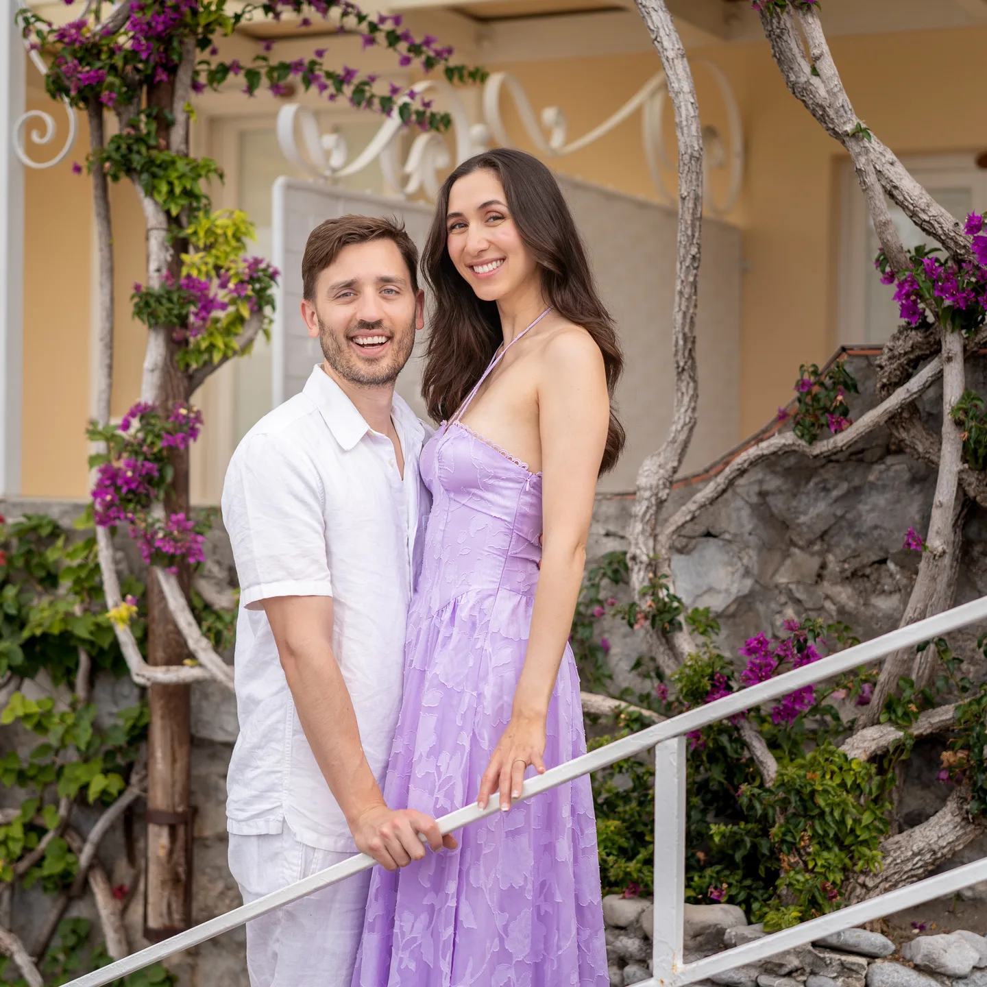 The couple smiling beneath the flowers