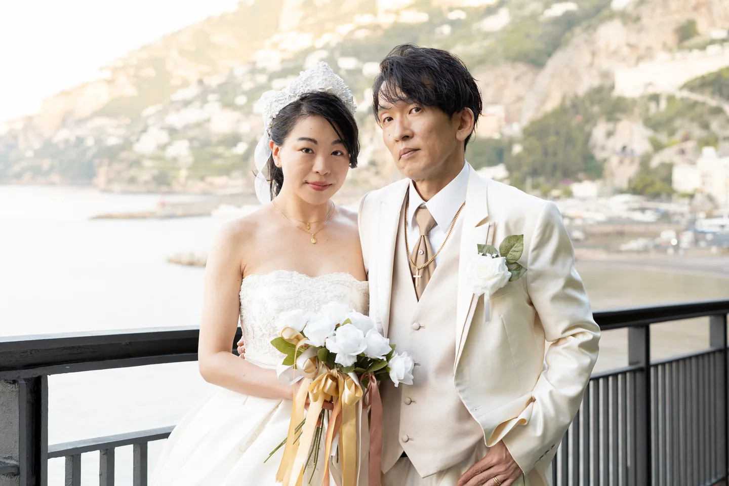 The couple holding their bouquet beside the waterfront railing