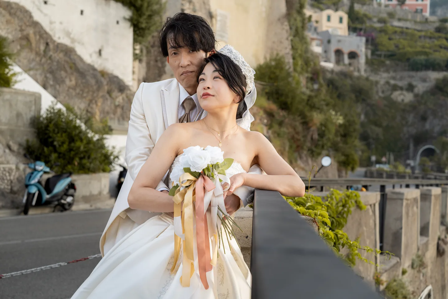 The couple leaning over a railing with their bouquet