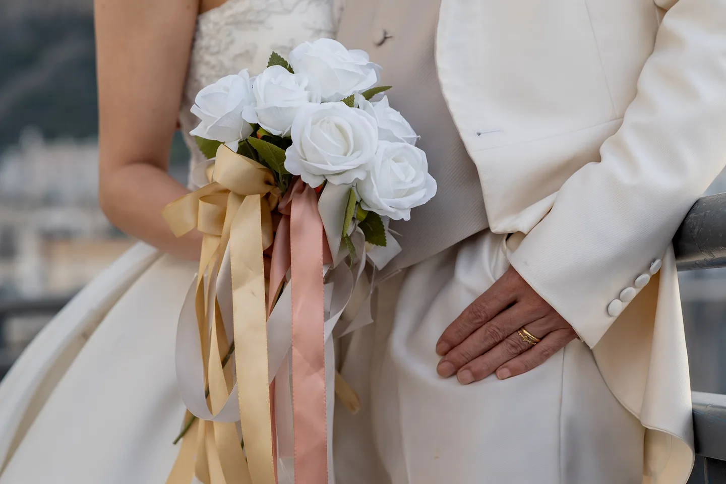 A detail of the white bouquet, ribbons and wedding clothes