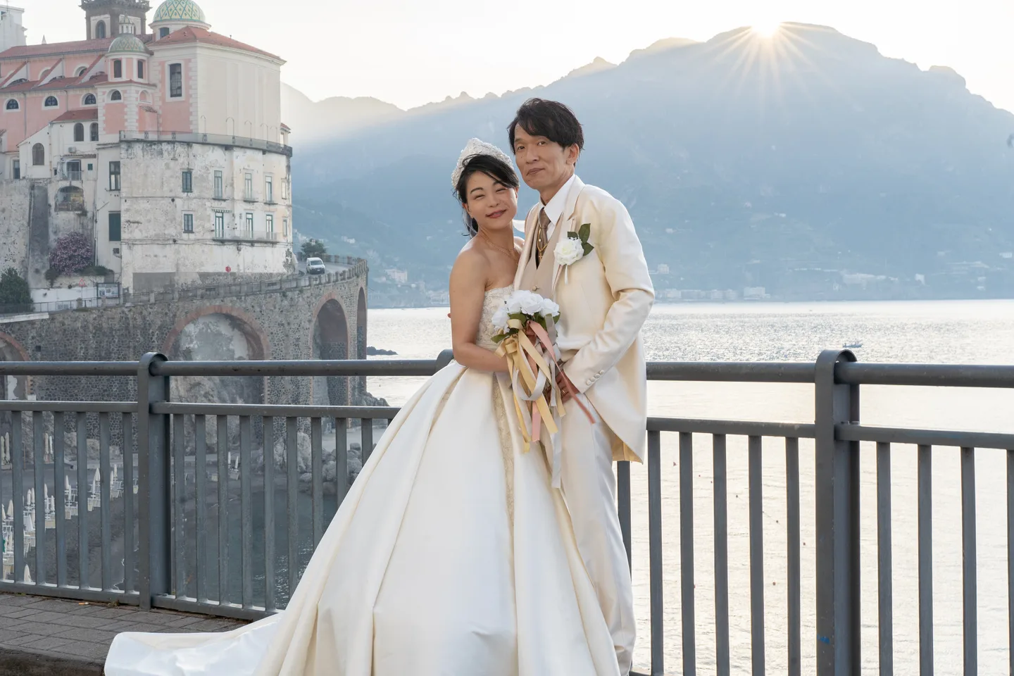 The couple standing together as sunlight reaches the mountains