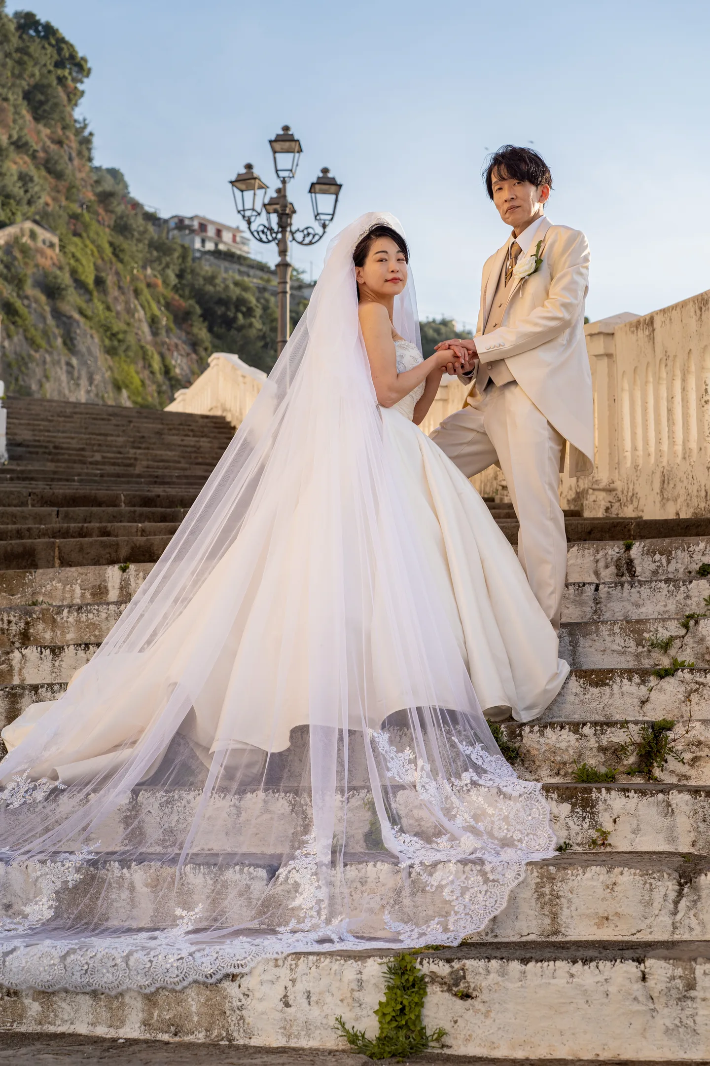 The couple on the seaside steps with the dress train spread below them