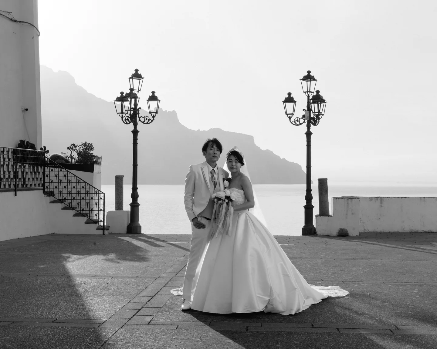 A black-and-white portrait of the couple and wedding dress on the terrace