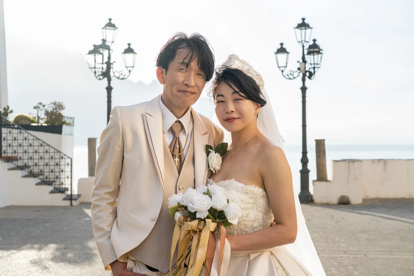 The couple smiling beside the seaside street lamps