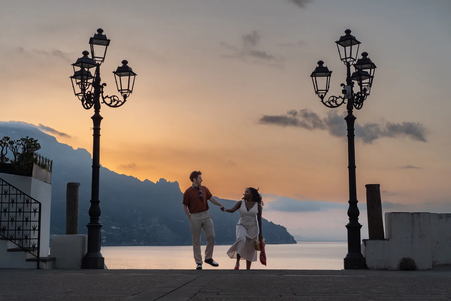 The couple beneath street lamps against a colourful dawn sky