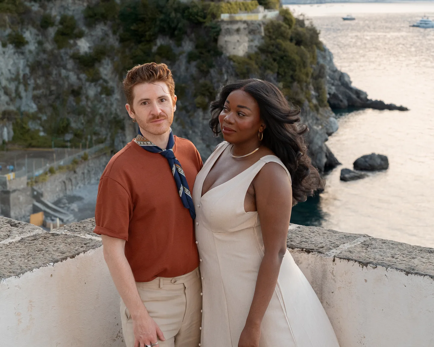 A portrait of the couple beside the white terrace wall