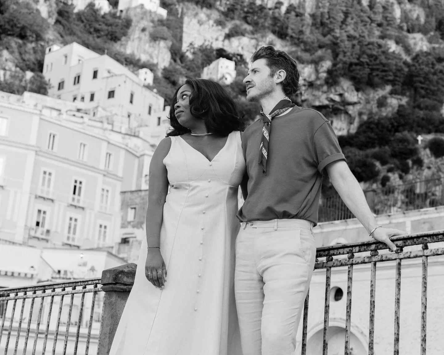 A black-and-white portrait of the couple beside the village railing
