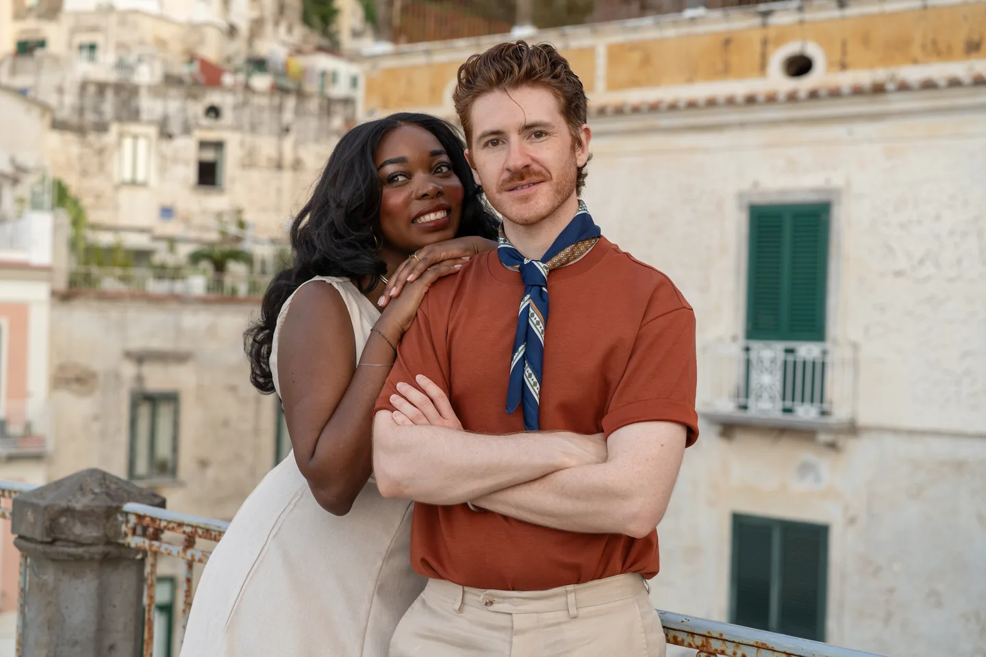The couple smiling together beside the stone railing